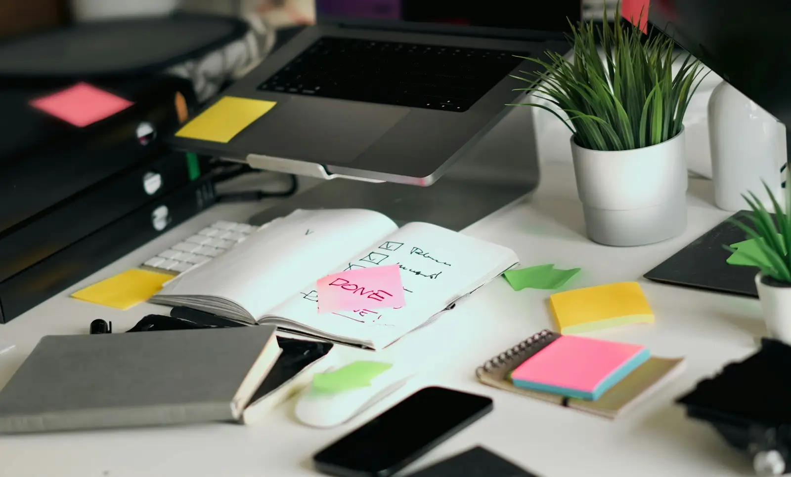 A busy desk with a laptop, notebooks and sticky notes