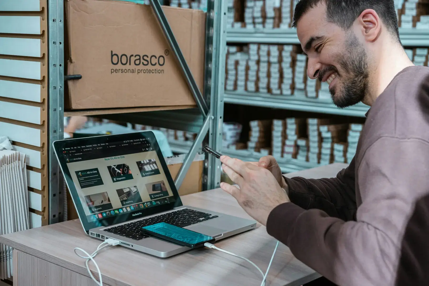 A business owner checking orders on a laptop among stock shelves